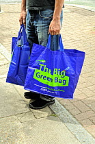 Man in street carrying The Big Green Bag, reusuable bag from Tesco, London, UK