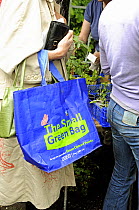 The Small Green Bag, reusable shopping bag from Tesco held by woman in queue at plant sale, London UK
