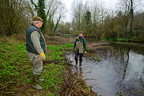 A member of staff from the Wildwood Trust, talks to landowner, during conservation efforts to improve water vole habitat on a stream by cutting trees to allow growth of bankside vegetation, East Malli...