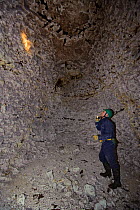 Kent Bat Group member surveying a denehole or chalk cave for hibernating bats, near Faversham, Kent, UK, January 2011. Model released.