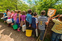 School children with equipment to do kick sampling, invertebrate identification, and release salmon fry in the River Haddeo, Bury, Exmoor National Park, Somerset, UK. May 2012. Editorial use only