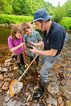 School children trying to identify invertebrates from River Haddeo, with Westcountry Rivers Trust (WRT) warden. Bury, Exmoor National Park, Somerset, UK. May 2012.