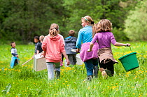 School children carrying equipment to release salmon fry in the River Haddeo and to do invertebrate kick samples with Westcountry Rivers Trust (WRT) warden. Bury, Exmoor National Park, Somerset, UK. M...