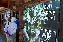 Sign with close-up portrait of an Osprey (Pandion haliaetus) outside entrance to the visitor centre at Dyfi Osprey Project, Powys, Wales, UK, May 2012.