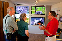 People watching screens showing footage from the Dyfi Osprey live web cam in the visitor centre, Dyfi Osprey Project, Powys, Wales, UK, May 2012.