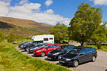 Parked cars at entrance to Creag Meagaidh National Nature Reserve, Badenoch, Scotland, UK, June 2012.