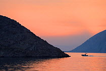 Boat sailing along Adriatic coast at dusk, Velebit Nature Park, Rewilding Europe area, Velebit mountains, Croatia June 2012