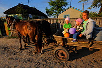 Family travelling by traditional horse and cart means, Letea, Danube delta rewilding area, Romania May 2012