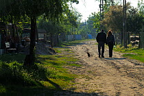 Couple walking down dirt road in Sfinthu Gheorghe, Danube delta rewilding area, Romania, June 2012