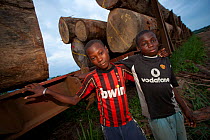 Two boys stand close to railway trucks loaded with  hardwood timber logs for export from Gabon