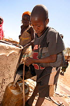 Gula boy drawing water from well; these people are Magreb Arab descendants originally from Sudan. Precious water is drawn from a communal well each day by women and children in the village of Bon near...