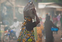 Street market with woman carrying bag of charcoal on her head. Maroua, Northern Cameroon, September 2009