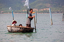 Family in round coracle style fishing boat in Baie du Cumon, Vietnam November 2011