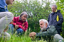 Botanist Ray Woods identifying grass species for participants on plant identification course. Radnorshire Wildlife Trust Nature Reserve, Wales, UK, June.