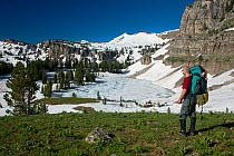 Backpacker above frozen Marion Lake along the Teton Crest Trail in Grand Teton Natoinal Park. Wyoming, USA, July 2011 Model released