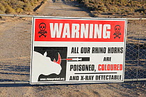 Warning sign explaining that rhino horns within reserve are poisoned and coloured. Private game reserve, near Ceres, Karoo, South Africa, November