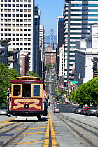Cable car crossing California Street with Bay Bridge backdrop in San Francisco, California, USA, June 2011
