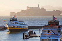Alcatraz Island, seen behind ferries at dusk, San Francisco, California, USA, June 2011