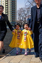 Young girls in colourful traditional dress walking along pavement in Pyongyang, Democratic Peoples' Republic of Korea (DPRK), North Korea, 2012