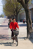 Woman riding bicycle in Wonsan, Democratic Peoples' Republic of Korea (DPRK), North Korea, 2012
