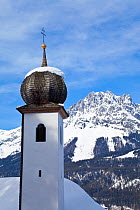 Church tower with onion dome at Ellmau ski resort, Wilder Kaiser mountains beyond, Tirol, Austria, 2009