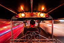 Tuk Tuk or auto rickshaw in motion at night, Bangkok, Thailand, 2010. Model released.