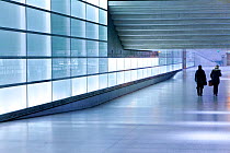 People commuting through glass walled passageway in modern building, Berlin, Germany, 2009