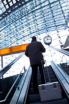 Man travelling up escalator towards the platform clock, modern train station, Berlin, Germany 2009