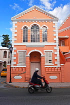 Man on a scooter riding past white stone roofs and pastel architecture of the historic town of St. George, an UNESCO World Heritage Site, St George's Parish, Bermuda 2007