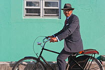 Businessman riding his bicycle in front of a colourfully painted wall, Hamilton, Bermuda, 2007 model released