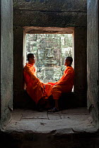 Two buddhist monks relaxing in the Bayon Temple, Angkor Wat, Siem Reap, Cambodia 2010. Model released.