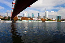 River scene with city skyline in background, bridge overhead, Frankfurt, Hesse, Germany 2010