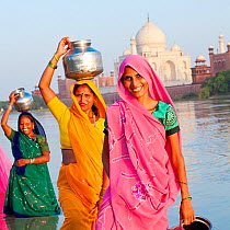 Women in colourful Saris collecting water, across the Jumna (Yamuna) river from Taj Mahal, UNESCO World Heritage Site, Agra, Uttar Pradesh, India, 2011, model released