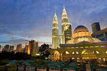 Mosque in the KLCC city park grounds at the base of Petronas Towers at night - 88 storey steel clad twin towers with a height of 451.9 metres - the iconic symbol of Kuala Lumpar, both illuminated at n...