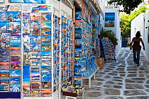 Lady walking alongside shop selling postcards, Mykonos (Hora), Cyclades Islands, Greece, 2010
