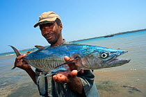Fisherman holding a Wahoo (Acanthocybium solandri) an oceanic fish sometimes caught close to reefs and rocks, Wasini Island, off the coast of Kenya, February 2011