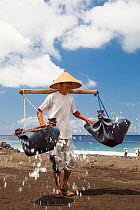 Man collecting black sand in an area which is one of the locations for producing fine restaurant quality salt, most of which is shipped to Japan, Kusimbi Beach, Bali, Indonesia 2009. No release availa...