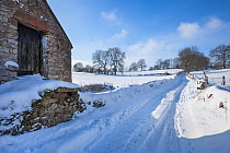 Barn next to country lane / track leading out of Bonsall village after heavy snow, Peak District National Park, Derbyshire, UK. January.