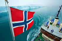 Norwegian flag set on M/S Stockholm and ice front of Brasvellbreen seen from crow's nest, Austfonna, Nordaustlandet, Svalbard, Norway, July 2012