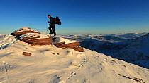 Man walking through snow to reach summit of Coigach, near Ullapool, Scotland, UK, December 2011. Model released.