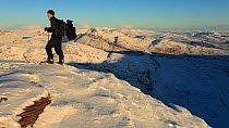 Man walking through snow to reach summit of Coigach, near Ullapool, Scotland, UK, December 2011. Model released.
