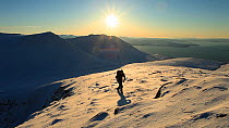 Man walking through snow climbing Coigach, near Ullapool, Scotland, UK, December 2011. Model released.