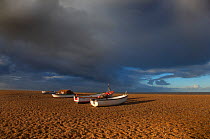 Boats on Cley Beach with stormy clouds above, UK November 2012