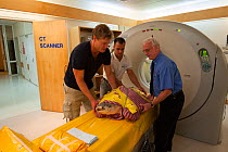 Dr Chris Brown from Channel 10's Bondi Vet TV show, x-ray technical expert Peter Lanski & volunteer Christian Miller with injured turtle 'Angie' coming out of CT Scan xray. Queensland, Australia, Dece...