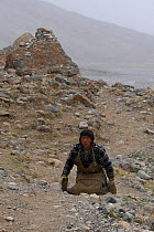 Prostrator about to perform body-length prostrations over the entire length of the circumambulation around Mount Kailash. The pilgrim bends down, kneels, prostrates full-length, makes a mark with his...