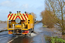 Highway maintenance vehicle driving through floods on severely flooded A361 between East Lyng and Burrowbridge across Lower Salt Moor after weeks of heavy rain, Somerset Levels, UK, January 2013.