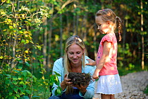 Woman and child looking at a thrush (Turdidae) nest. Southern Estonia, August. Model released