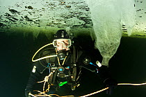 Scuba diver under ice with stalactite ice formation, Arctic circle Dive Center, White Sea, Karelia, northern Russia, March 2010