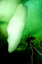 Scuba diver under ice next to ice formation, Arctic circle Dive Center, White Sea, Karelia, northern Russia, March 2010