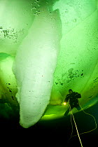 Scuba diver under ice next to large ice formation, Arctic circle Dive Center, White Sea, Karelia, northern Russia, March 2010. No release available.